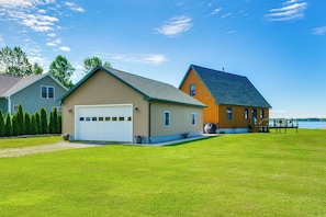 A two-story house with a garage, a deck, and a view of a lake. - Fisherman's Retreat on Lake Ontario, Near Marina (Cape Vincent)