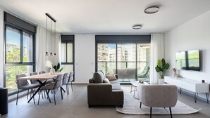 Un salon moderne comprenant un coin repas, de grandes fenêtres, un téléviseur à écran plat et une vue sur les immebles.