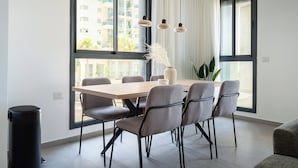 Un espace de salle à manger moderne avec une table en bois, des chaises à revêtement gris et des luminaires suspendus.