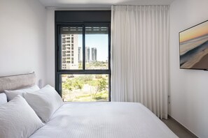 Habitació d'hotel amb un llit gran, una finestra amb cortines i vista a gratacels.
