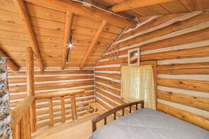 A log cabin room with a bed, wooden walls, a wooden staircase, and a window with curtains. - Pigeon River Escape Surrounded by State Land! (Vanderbilt)