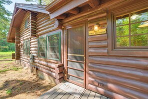 A log cabin with a 'DOC'S WHITE PINE LODGE' sign, a wooden door, and a welcome mat. - Pigeon River Escape Surrounded by State Land! (Vanderbilt)