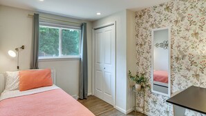 Ein Schlafzimmer mit einem Bett, einem Nachttisch, einem Spiegel, einem Fenster mit Vorhängen und einer Tür.