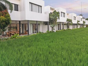 Un edificio residencial moderno con techo plano, ventanas grandes y un césped bien cuidado.
