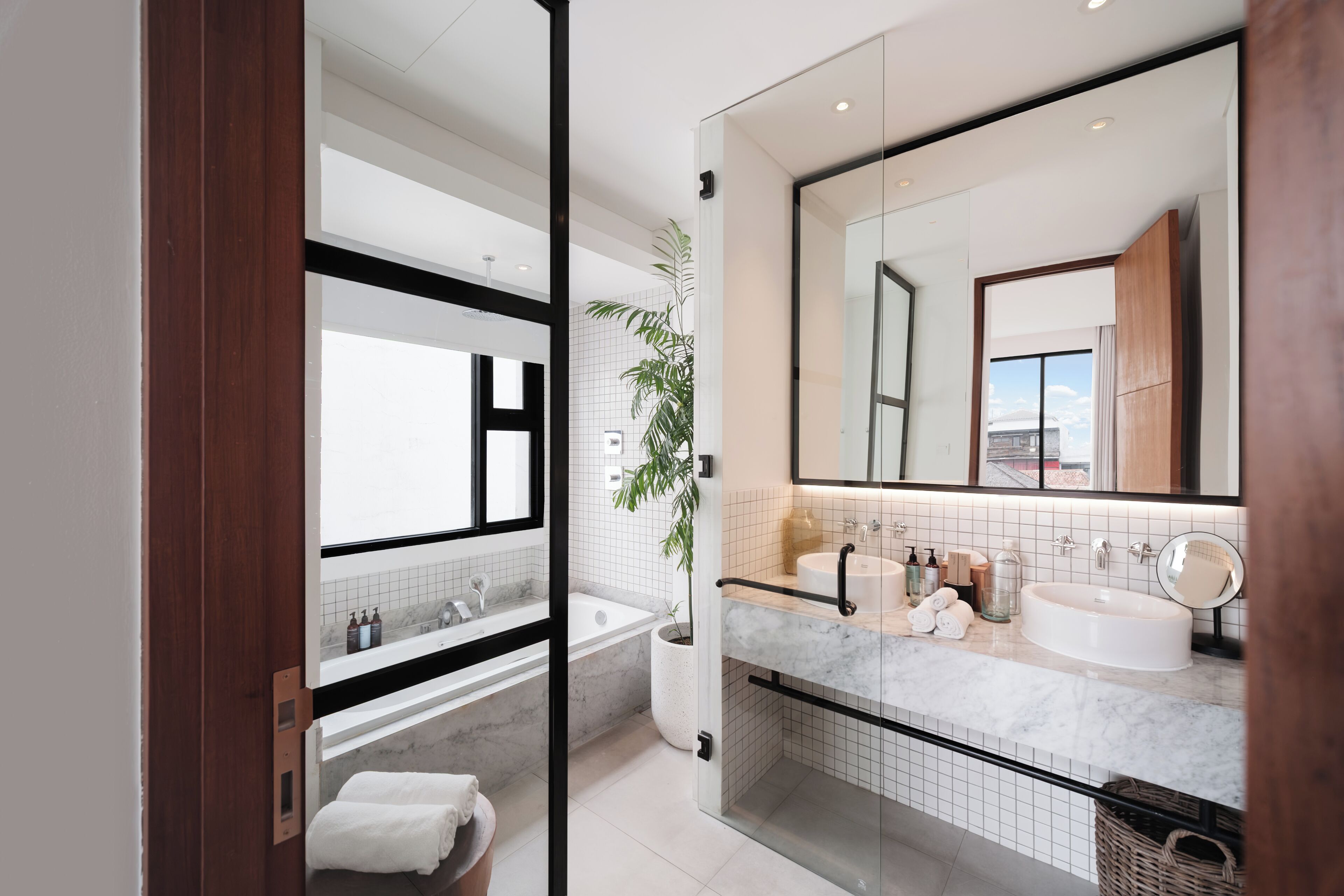 Un baño moderno con un espejo grande, una bañera, ducha y encimera de mármol.