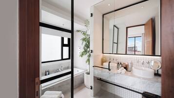 Un baño moderno con un espejo grande, una bañera, ducha y encimera de mármol.