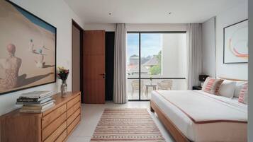 Ein modernes Schlafzimmer mit einem großen Bett, einer Holzkommode, einem Gemälde und einem Balkon mit Blick.