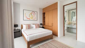 A modern bedroom with a large bed, wooden wardrobe, bedside tables, and a bathroom visible through an open door.