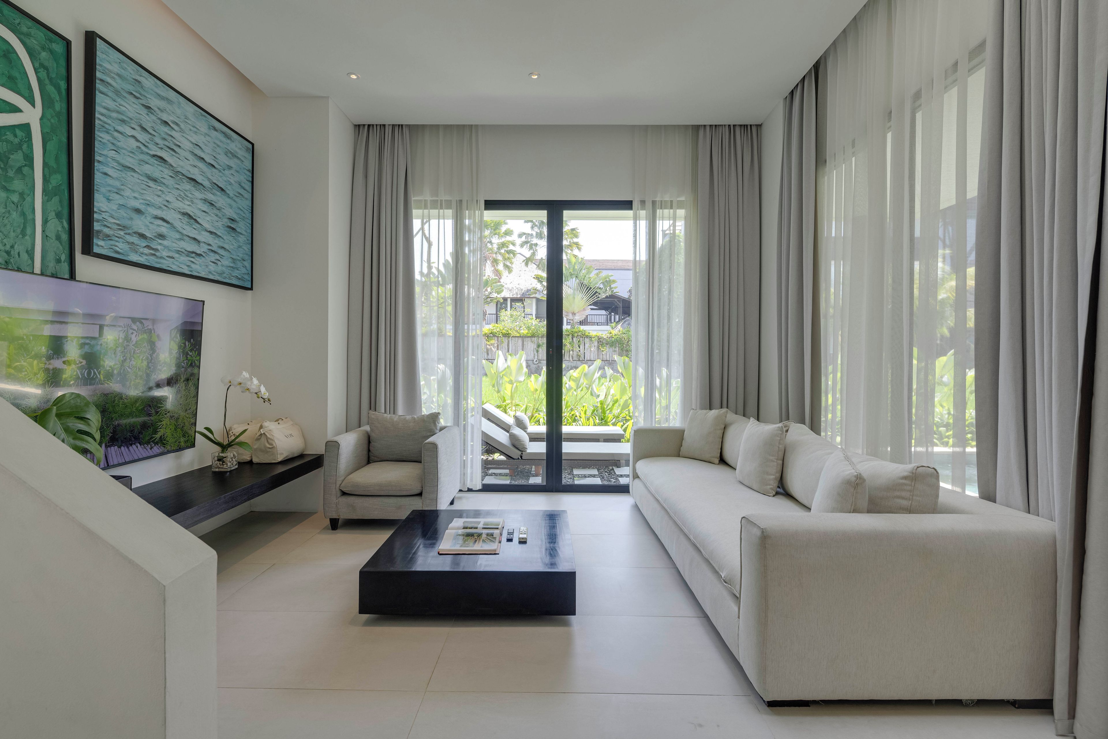 A modern living room with a sofa, coffee table, and a large window with curtains.