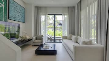 A modern living room with a sofa, coffee table, and a large window with curtains.