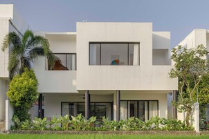 A modern two-story building with a flat roof, large windows, and a balcony.
