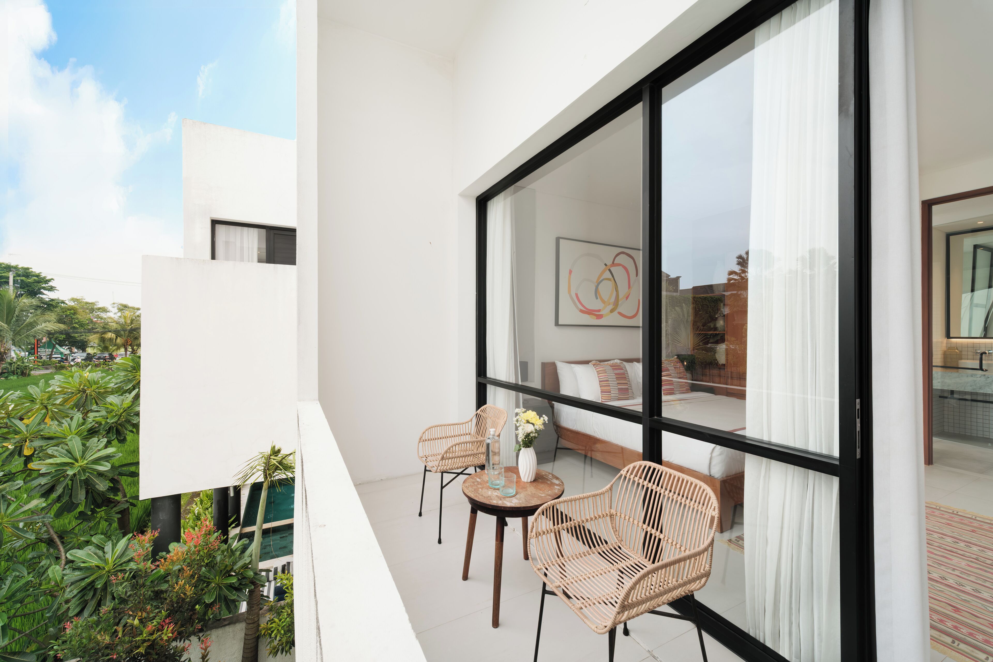 A balcony with wicker chairs, a small table, and a vase of flowers.