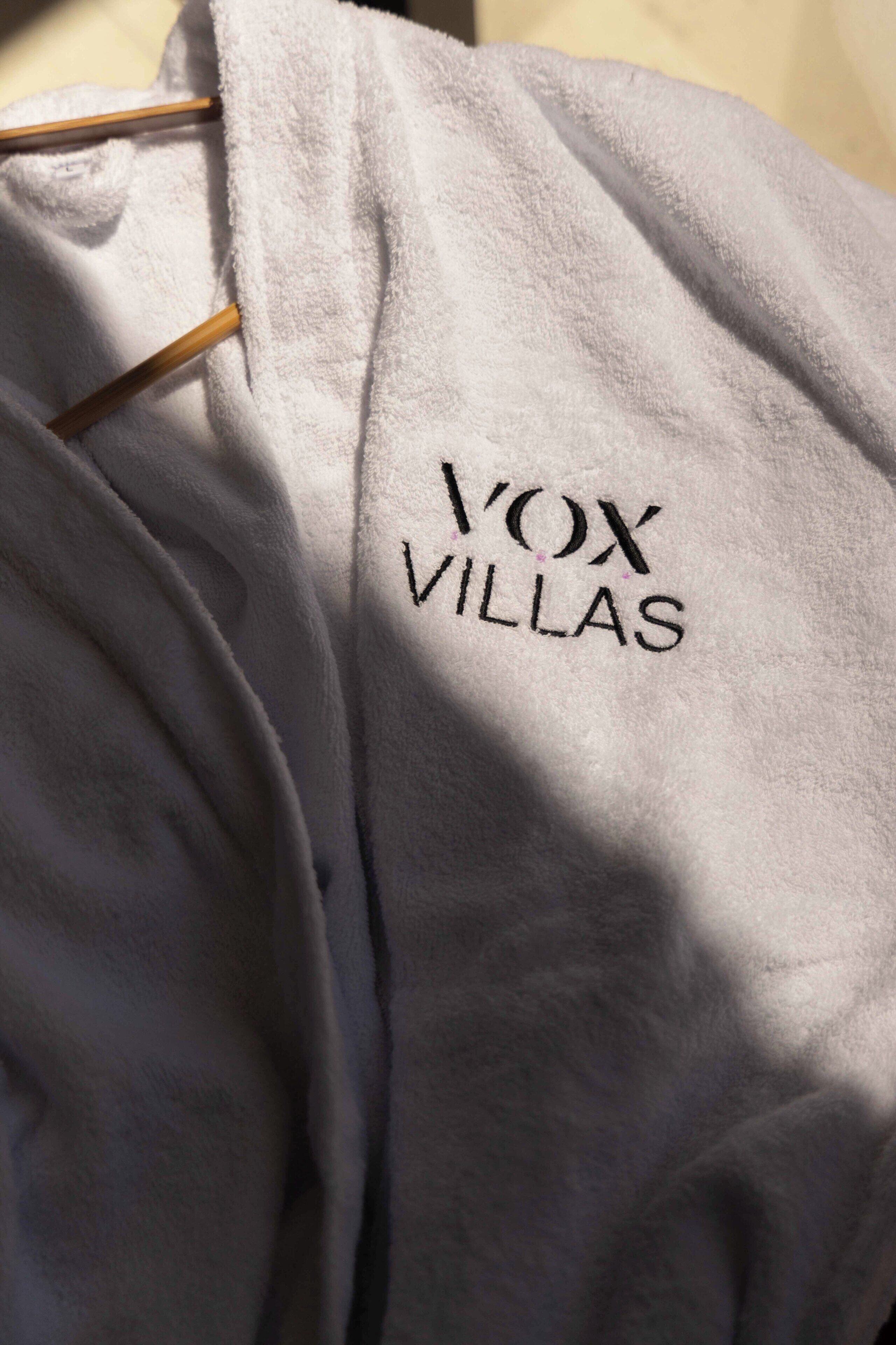 A white towel with the text 'V'OX VILLAS' on it.