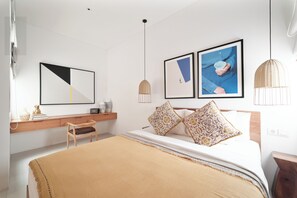 Un dormitorio moderno con cama, escritorio, silla y dos lámparas colgantes fijadas a la pared.