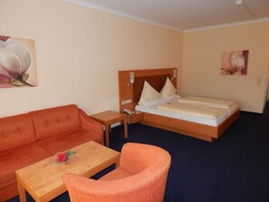A hotel room with a bed, a sofa, a chair, a small table, and two paintings on the walls. - BSW Schwarzwaldhotel Baiersbronn (Baiersbronn)