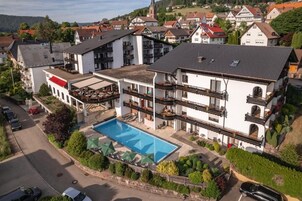 Un hotel de varios pisos con piscina, balcones y vistas del barrio circundante.
