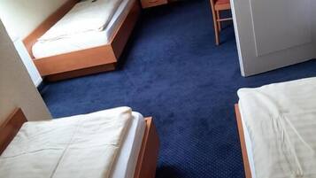 A room with two beds, a wardrobe, a chair, and a small table.