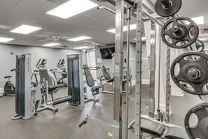 Ein Fitnessraum mit Gewichtstrainern, Trainingsgeräten und einer Spiegelwand.