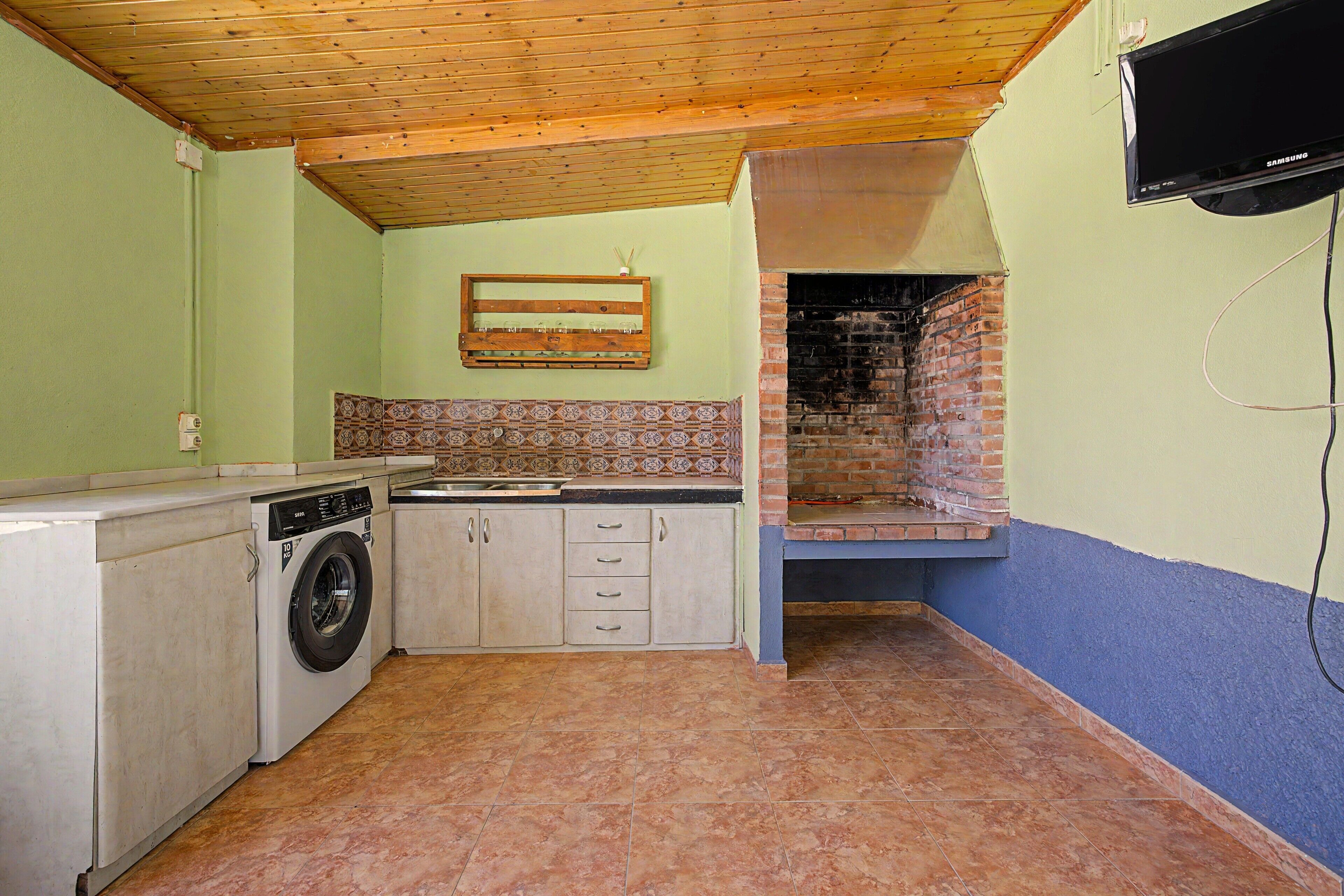 Una cocina compacta con lavadora, salpicadero de azulejos y horno de ladrillo.