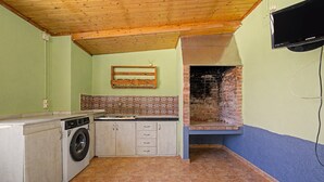 A compact kitchen with a washing machine, a tiled backsplash, and a brick oven.