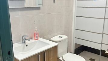 Ein Badezimmer mit Waschbecken, Toilette und Duschbereich.