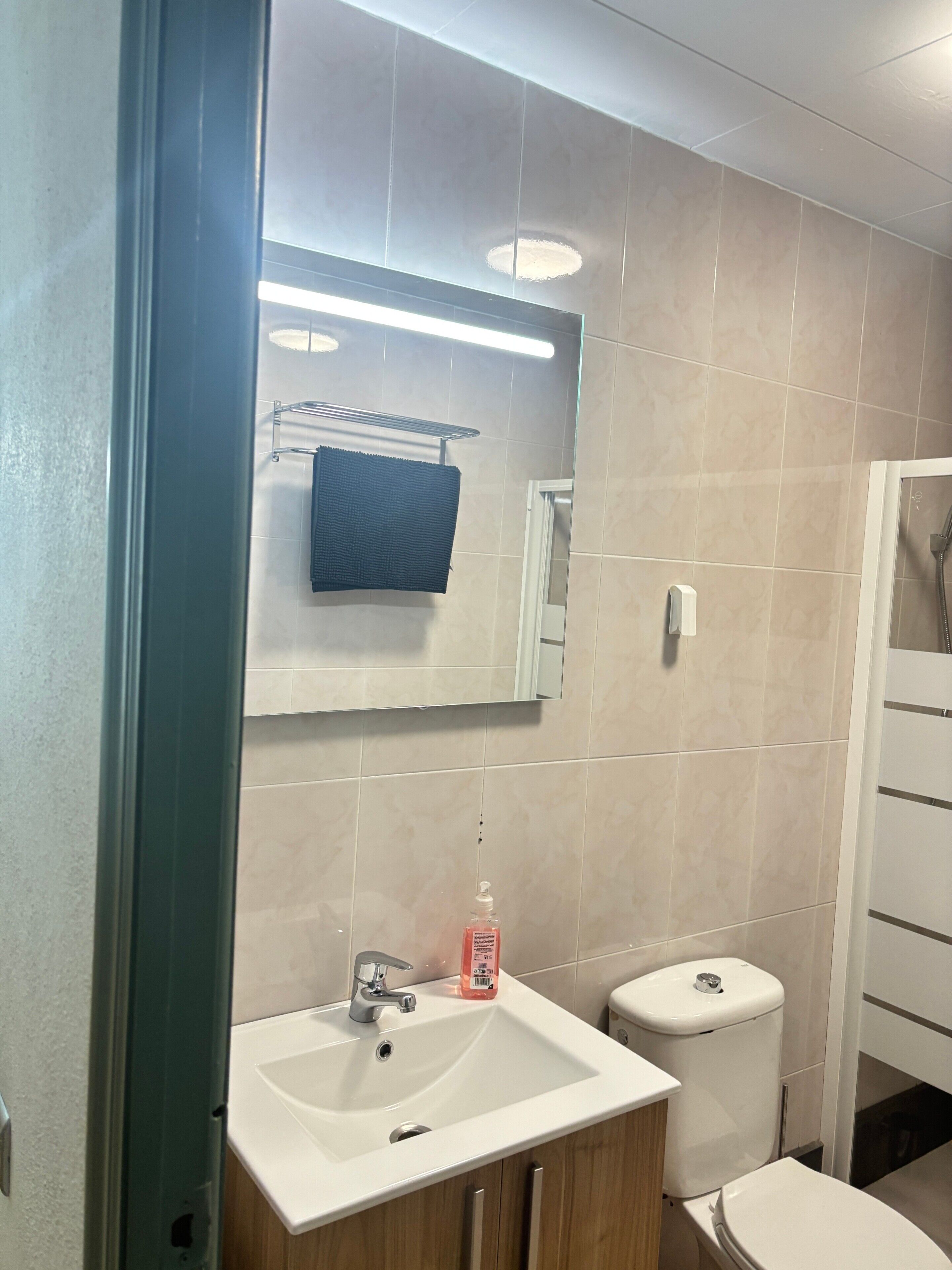 Un baño moderno con un lavabo blanco, un espejo y un inodoro.