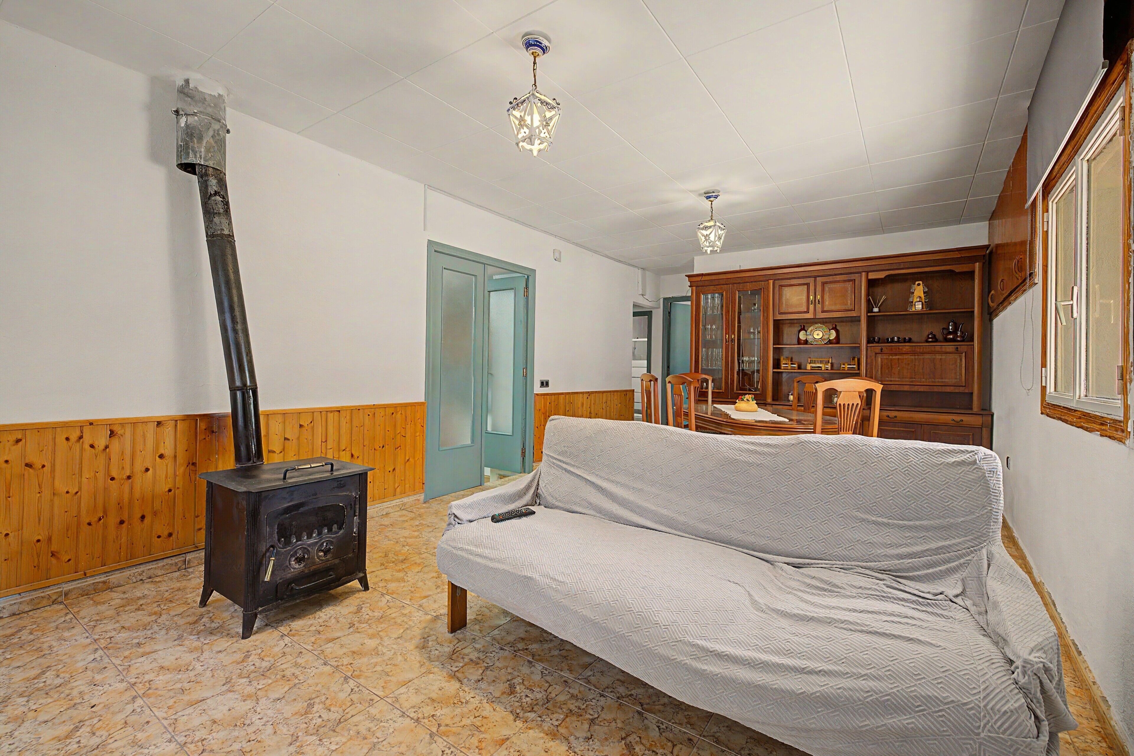 Une pièce comprenant un canapé, une armoire en bois, un poêle et un lustre.
