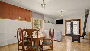 A dining area with a round table, wooden chairs, and a television on the wall.