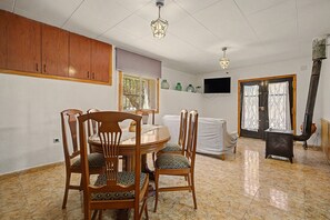 A dining area with a round table, wooden chairs, and a television on the wall.