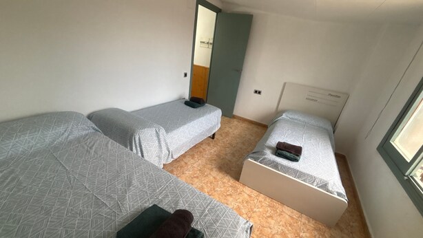 A small, clean room with two single beds, a door, and a window.