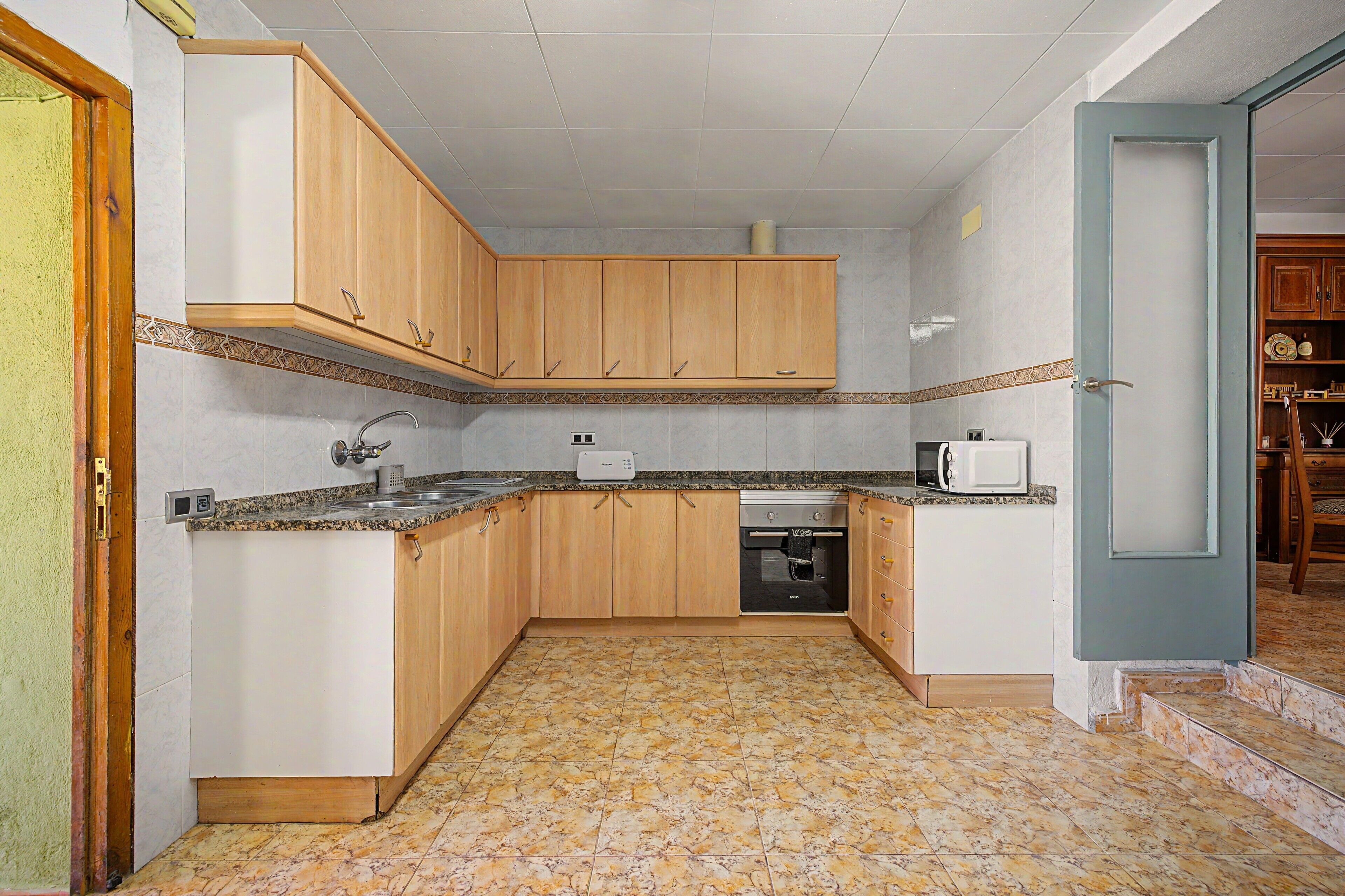 Una cocina compacta con armarios de madera, microondas integrado y lavavajillas.