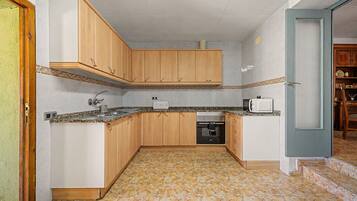 Una cocina compacta con armarios de madera, microondas integrado y lavavajillas.