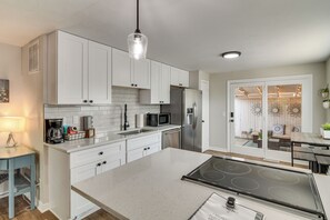 A modern kitchen with white cabinetry, a stainless steel refrigerator, a microwave, and a gas stove. - 12 Mi to Red Rocks, Dtwn Denver! Townhome w/ Patio (Arvada)