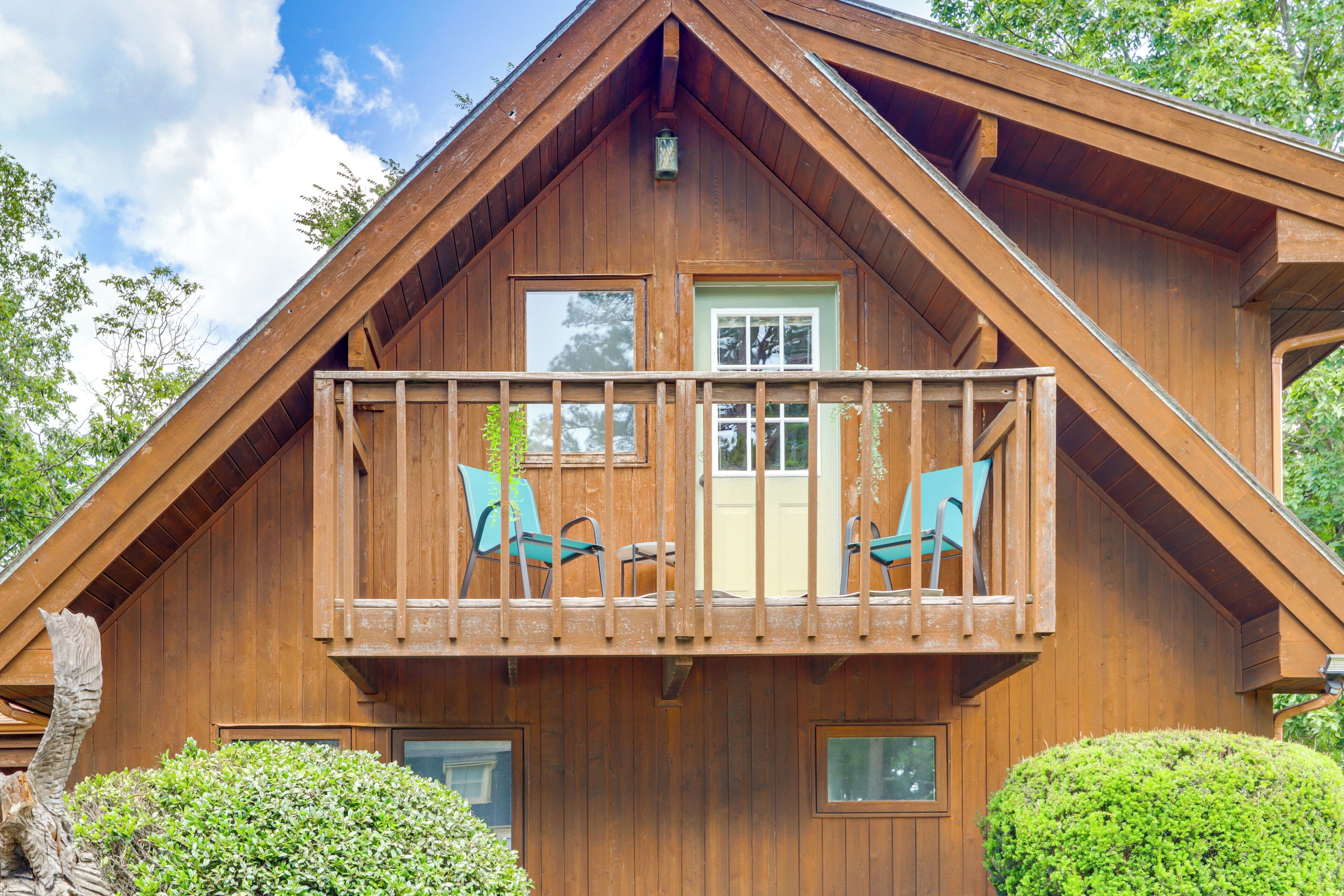 Een houten chalet met een balkon, een deur en ramen.