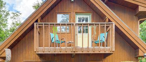 Een houten chalet met een balkon, een deur en ramen.