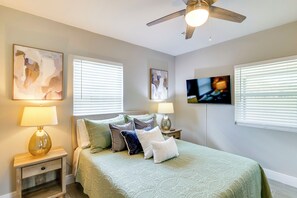 Ein Schlafzimmer mit einem Bett, zwei Nachttischen, einem Deckenventilator und Kunstwerken an den Wänden.
