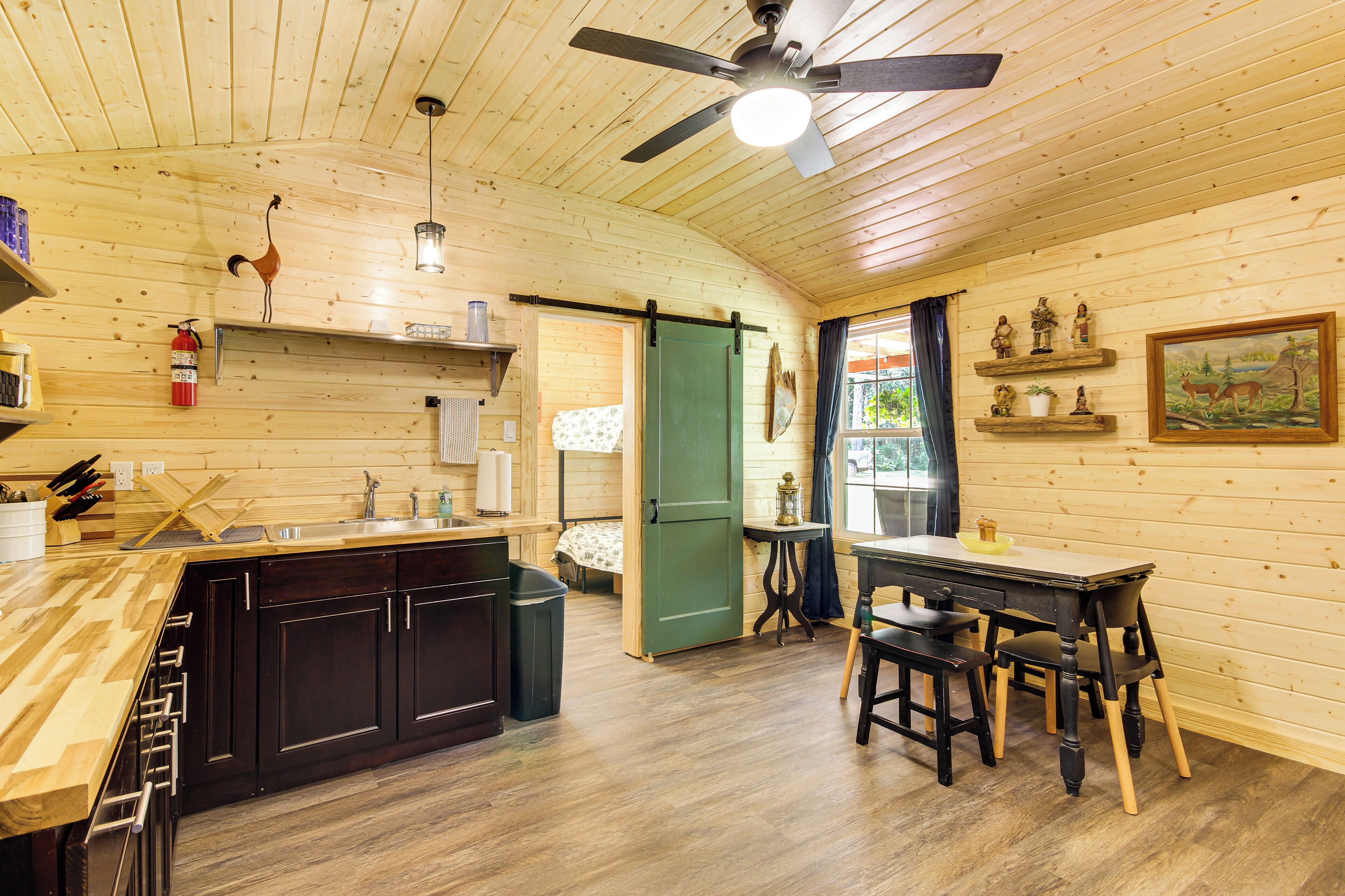 A wooden interior with a kitchen, dining area, and a door leading to another room.