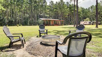 A cabin with a porch, a fire pit, and two Adirondack chairs.