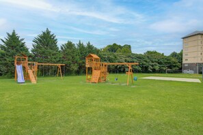 Une aire de jeux avec deux cabanes en bois et des balançoires.