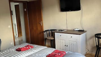 Ein Hotelzimmer mit einem Bett, einem Schreibtisch, einem Sessel, einem Fernseher und einer Holzbalkendecke.