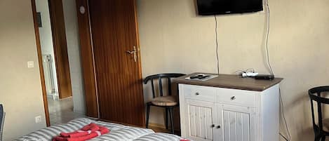 Habitación de hotel con cama, escritorio, silla, televisor y techo de madera.