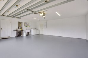 Ein sauberes, leeres Zimmer mit weißen Wänden und einem grauen Boden, ausgestattet mit einer Küchenzeile, die einen Herd, ein Waschbecken und Stauraumschränke umfasst.
