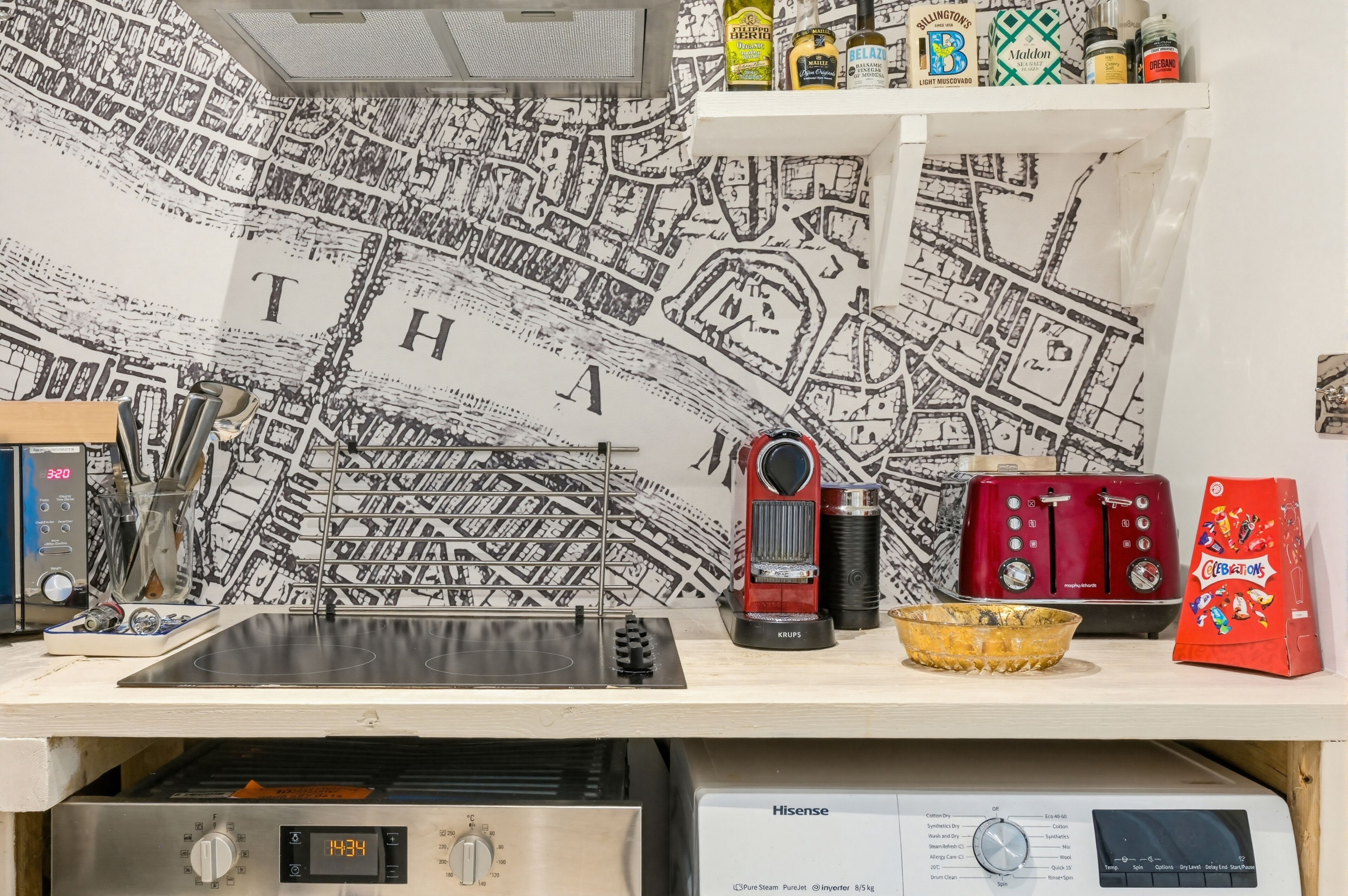 Une cuisine avec un mur décoré d’une carte, une machine à café, un grille-pain et divers ustensiles de cuisine.
