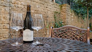 A bottle of Puligny-Montrachet wine with two glasses on a metal table with a decorative backrest. - Pet Friendly Studio in Fulham, Sleeps 2 (London)