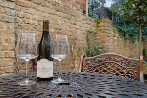Eine Flasche Puligny-Montrachet Wein mit zwei Gläsern auf einem Metalltisch mit dekorativer Rückenlehne.