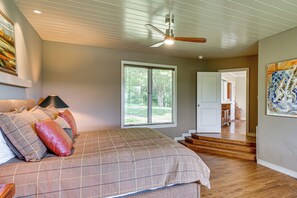 A bedroom with a bed, a ceiling fan, a window with blinds, and a door leading to another room. - Mountain Home Near Lake Glenville w/ Scenic Views (Cullowhee)