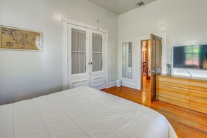 A bedroom with a bed, a dresser, a television, and a door leading to another room. - Walk to the Alamodome! Quirky Gem w/ Private Patio (San Antonio)