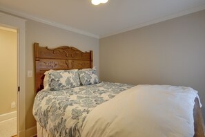 Un dormitorio con cabecera de madera, edredón estampado de flores y cubrecama blanco.