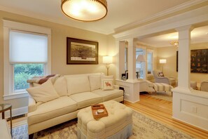 A living room with a beige sofa, a coffee table, and a framed map on the wall. - 'The Hand House!' Walk to Downtown & Race Course (Saratoga Springs)