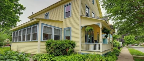 Ein zweistöckiges Haus mit Veranda, großen Fenstern und einem Schornstein.